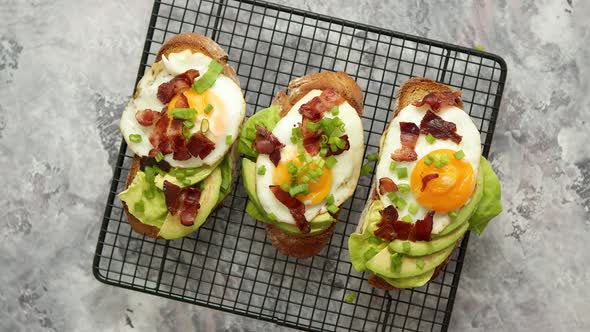 Tasty Delicious Homemade Toasts with Fried Egg, Bacon, Avocado, Lettuce and Chive