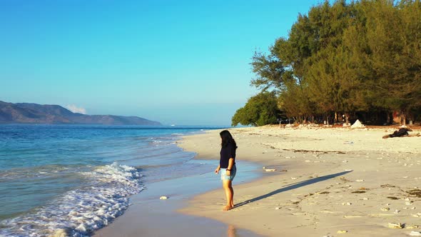 Sexy happy lady on photoshoot having fun at the beach on sunny blue and white sand background 4K