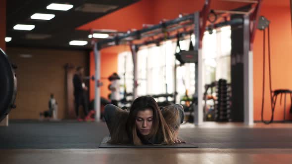 Attractive Longhaired European Woman Workout in Modern Gym with Variety of Equipment on Background