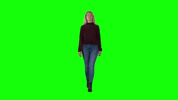 Blonde Girl in Pomegranate Sweater, Jeans and Boots Going Against a Green Screen. Slow Motion