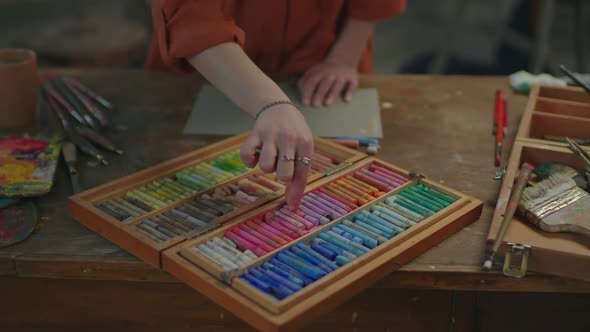Closeup of Artist Hands Selecting Pastel Crayons From Set