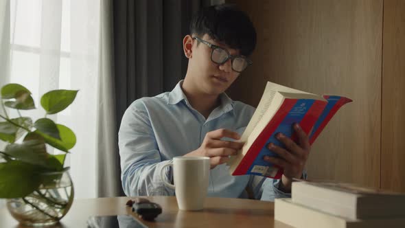 Young Attractive Asian Vietnamese Man is Busy Working Learning on Desk Book at Home Data Analyst