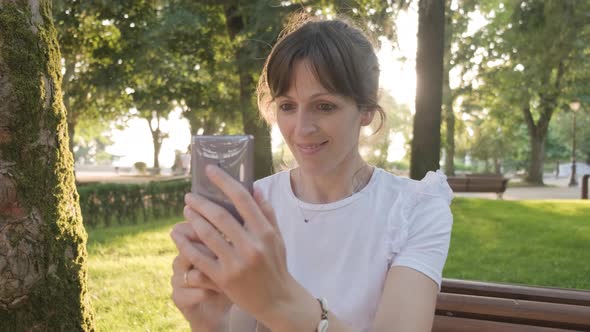 A Woman Filming A Selfie Video using her Phone while Smiling, Handheld Shot