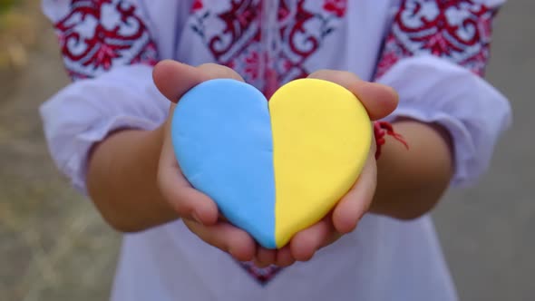 A Child Holds a Heart of the Ukrainian Flag