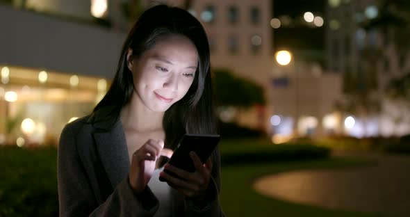 Woman use of mobile phone for online at outdoor at night