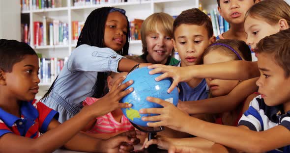 School kids studying globe in library