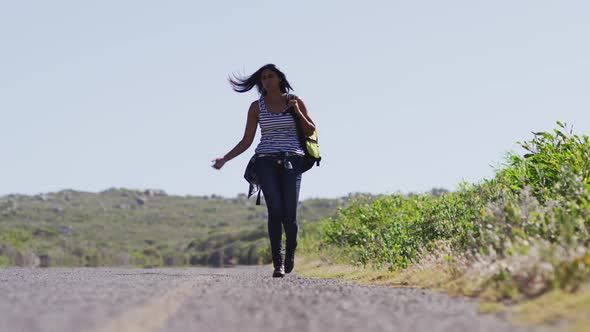 African american woman with backpack walking on a roadside highway