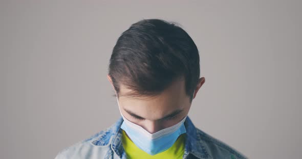 Young Man in Medical Mask Raising His Head and Staring at Camera