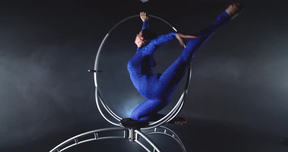 Pretty Woman in Blue Costume is Spinning in a Hoop and Doing Gymnastic Tricks