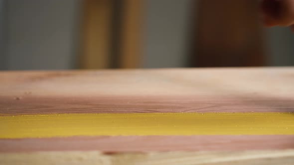 Painting Wood with Yellow Paint Using Brush Closeup