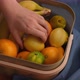 A woman putting her hand into a basket of fruit and pulling out a lemon - VideoHive Item for Sale