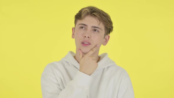 Pensive Young Man Thinking and Getting Idea on Yellow Background