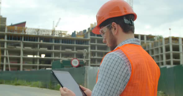 Modern Construction Engineer or Architect in Helmet at Construction Site Works with Industrial