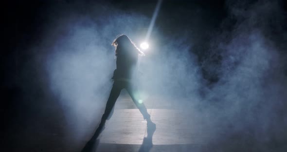 Young female dancer performing wild hip hop dance with strobe light and smoke background