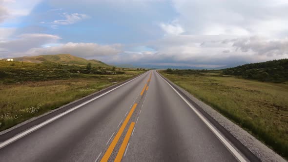 Driving a Car on a Road in Norway at Dawn