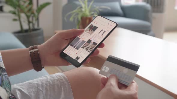 Close Up Of Man Hand Holding Smartphone And Credit Card And Doing Online Shopping At Home