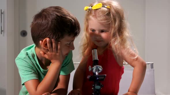 Little Boy in a Green Tshirt and a Cute Girl are Looking Through a Microscope