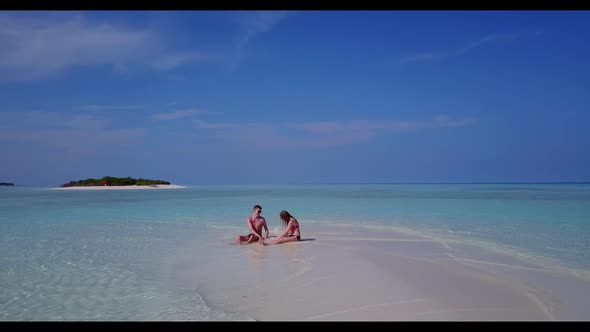 Family of two engaged on marine island beach lifestyle by shallow sea and white sand background of t