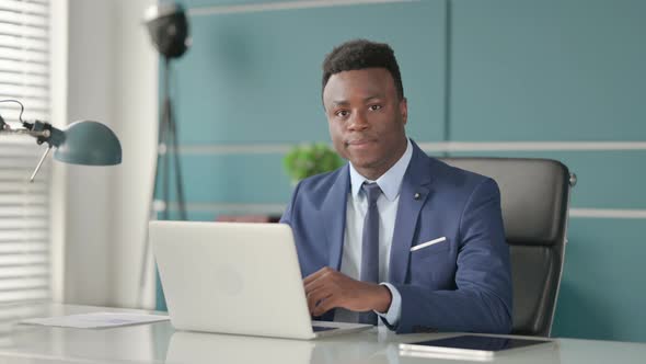 African Businessman Showing Thumbs Up Sign While Using Laptop at Work