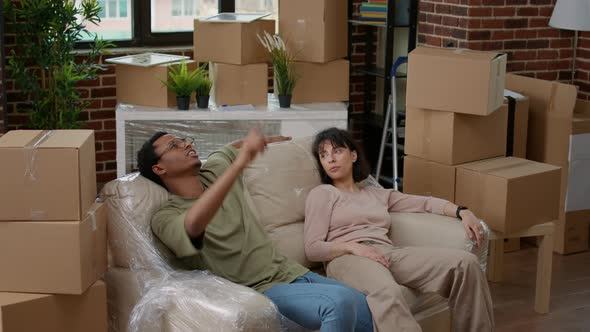 Tired Husband and Wife Relaxing on Couch After Unpacking Furniture