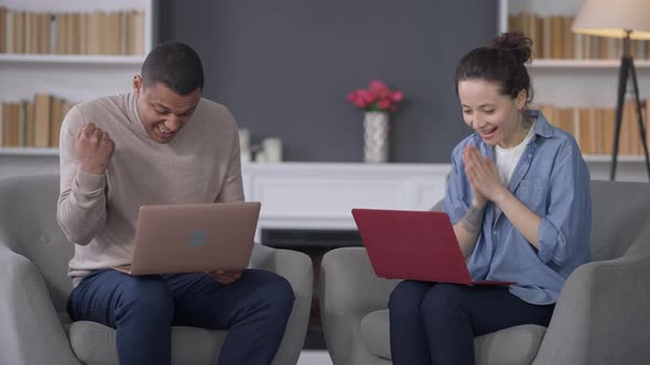 Excited Cheerful Interracial Couple of Startupers Giving Highfive Rejoicing Success of Business Idea