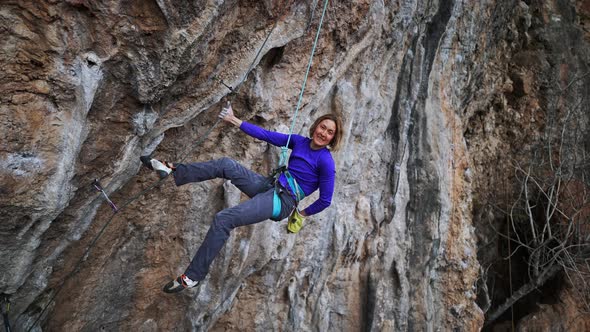 Slow Motion Smiling Tired Woman Rock Climber Hanging on Rope on Hard Challenge Route on Overhanging