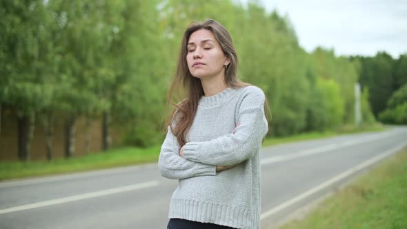 young woman waiting for a ride on a deserted country road