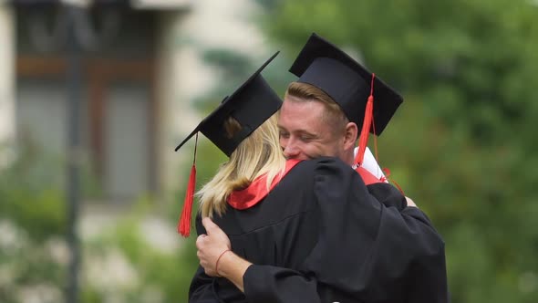 Cheerful Graduate Couple Embracing and Turning Around Enjoying Success