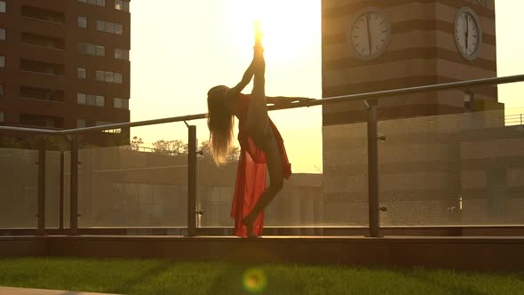 Beautiful Young Girl Dancing on the Street of a Modern City in the Sunset Light