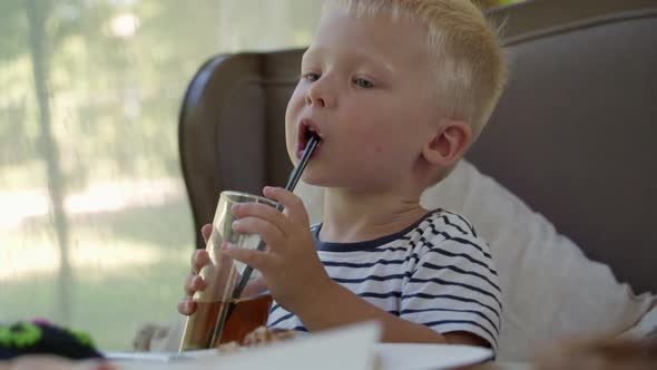 A cute little boy is sitting at a table in a cafe.