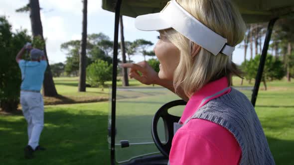 Happy female golfer sitting in golf buggy