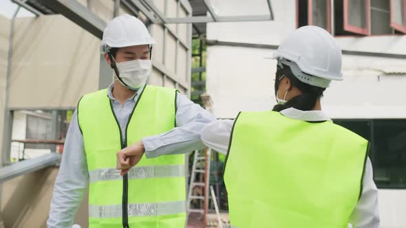 Asian workers people wearing protective mask, make elbow touch onsite of architecture due to covid