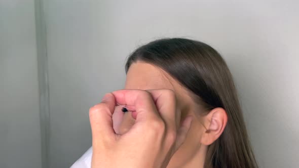 Beauty Master Draws a Contour of Eyebrows on a Young Girl