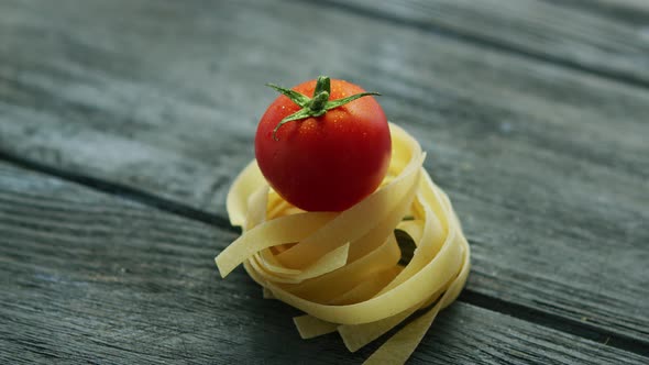 Closeup of Arranged Raw Bunch of Pasta with Small Red Cherry Tomato on Top