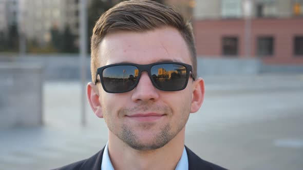 Portrait of Happy Businessman in Sunglasses with Cityscape at Background. Handsome Business Man