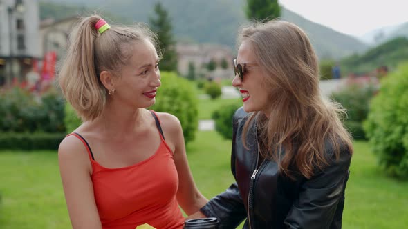 Portrait of Two Girlfriends with Bright Lipstick on the Background of Mountains