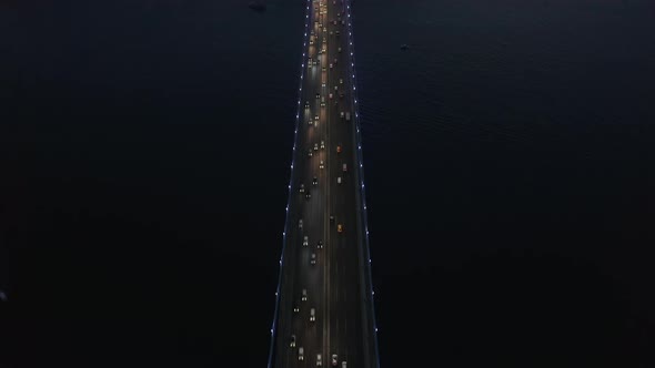 Birds Eye Top Down View of Bridge at Night with Car Traffic Looking Up Revealing City Skyline