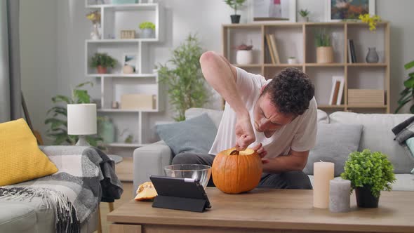Young Man Extracts Seeds From Pumpkin with a Spoon