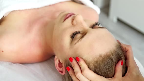 Beautician cosmetologist makes a relaxing head and hair massage