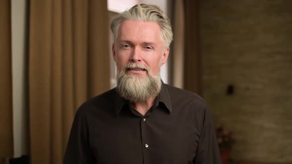 gray-haired bearded adult man listens attentively to something