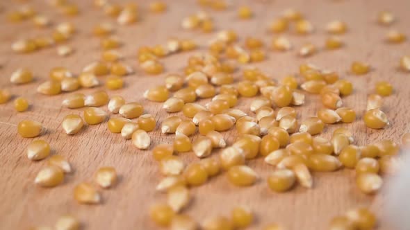 Dried corn kernels are spilled onto a wooden cutting board in slow motion 