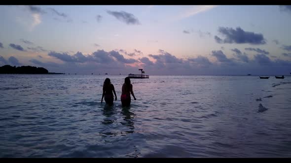 Girls relaxing on tranquil tourist beach adventure by blue ocean with clean sandy background of the 