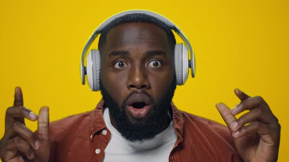 Portrait of Surprised African Guy Listening Music on Headphones in Studio