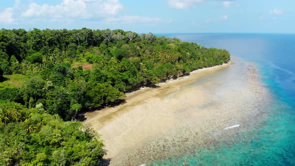 Aerial: flying over tropical Ai island white sand beach Banda Islands Indonesia