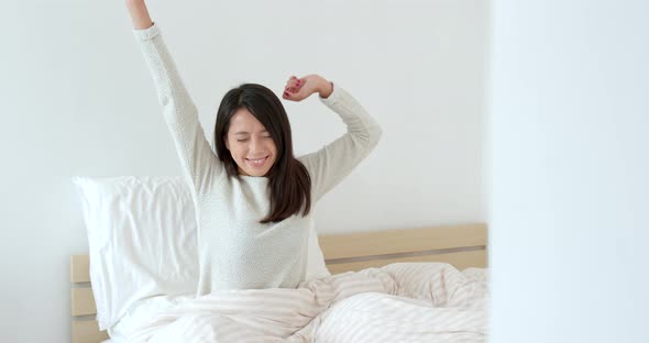 Woman wake up at morning and stretches hand on bed