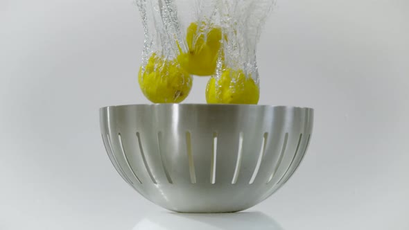 Lemons dropped in a fruit bowl in the water, Ultra Slow Motion alt