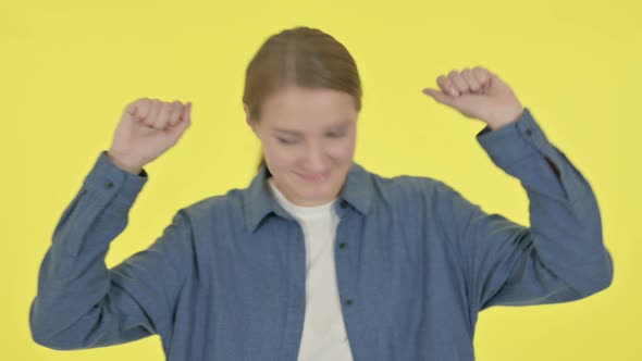 Young Woman Dancing in Joy on Yellow Background