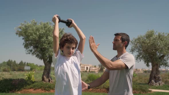 A Young Guy is Outside Exercising with a Personal Trainer