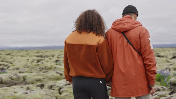 Hiking Couple Holding Hands through Moss Covered Landscape