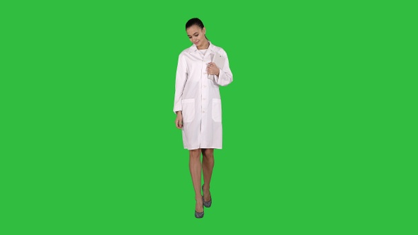 Woman doctor walking with tablet in hands on a Green Screen